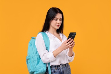 Student with smartphone and backpack on yellow background