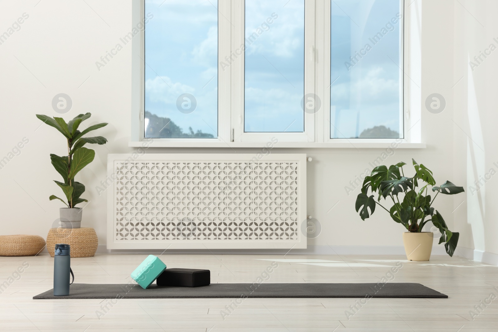 Photo of Exercise mat, yoga blocks and bottle of water on floor in room