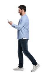 Handsome man with smartphone walking on white background