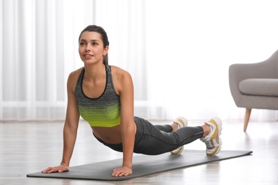 Photo of Young woman in fitness clothes doing exercise at home. Space for text