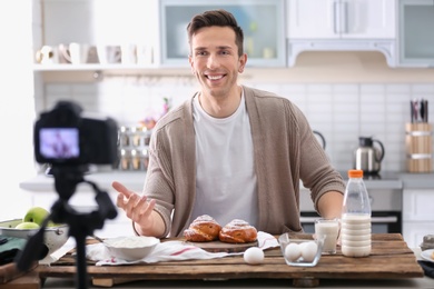 Young food blogger recording video on camera in kitchen