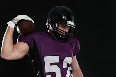American football player with ball on dark background