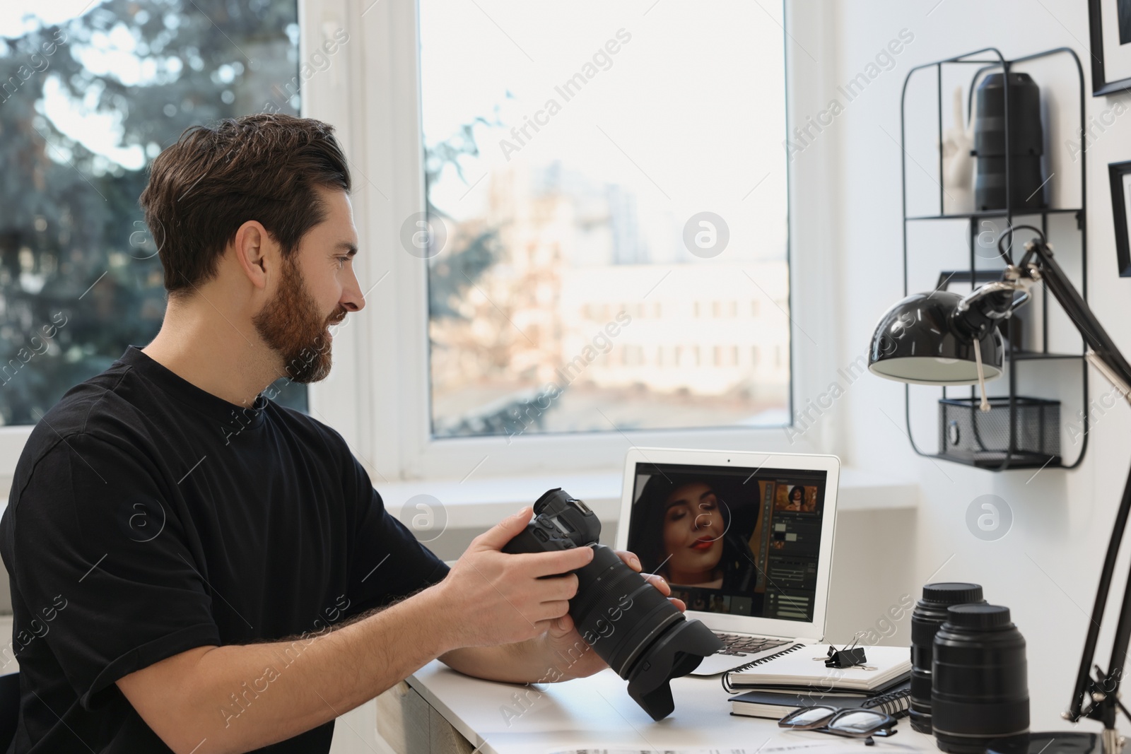 Photo of Professional photographer with digital camera at table in office, space for text