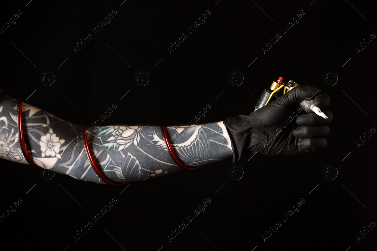 Photo of Tattoo artist with professional machine on black background, closeup