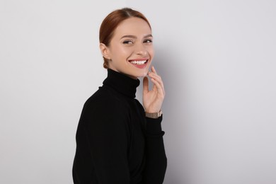 Portrait of beautiful young woman on light gray background, space for text