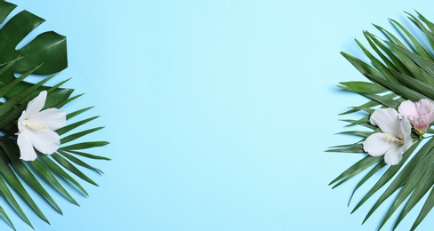 Photo of Flat lay composition with tropical leaves and Hibiscus flowers on blue background. Space for text