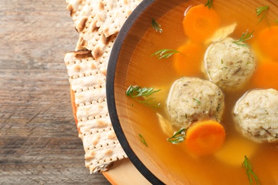 Bowl of Jewish matzoh balls soup on wooden table, closeup