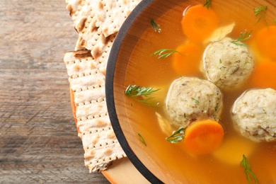 Photo of Bowl of Jewish matzoh balls soup on wooden table, closeup