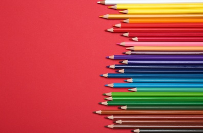 Photo of Colorful pencils on red background, flat lay. Space for text