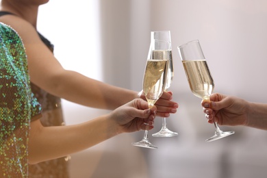 People clinking glasses of champagne against blurred background, closeup