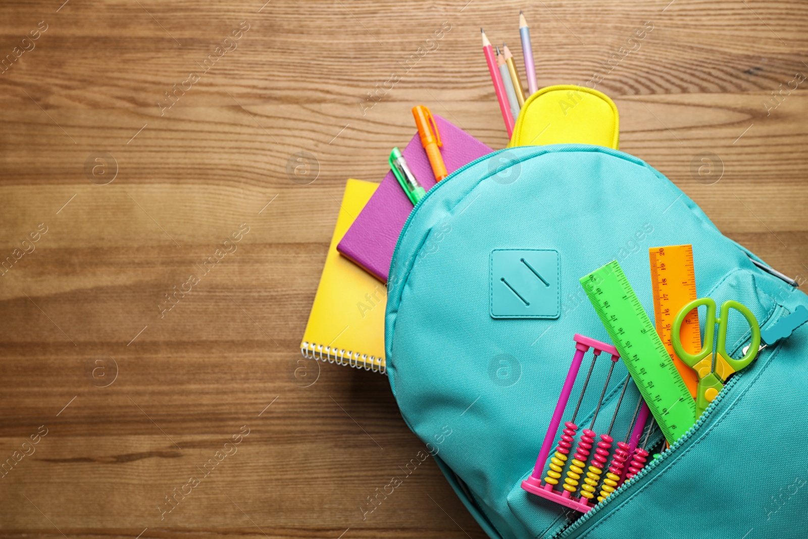 Photo of Stylish backpack with different school stationary on wooden table, top view. Space for text