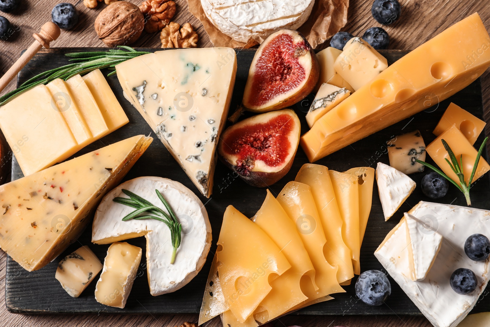 Photo of Different types of delicious cheese served on slate board, top view