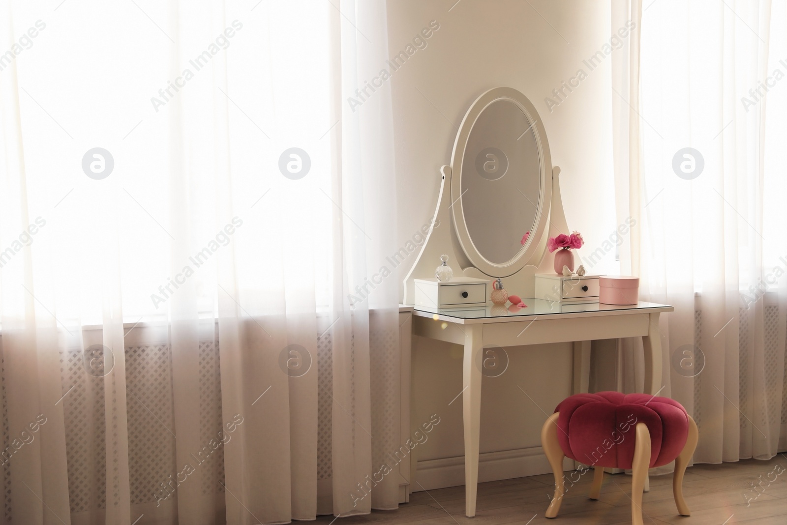 Photo of Elegant white dressing table and pouf in light room