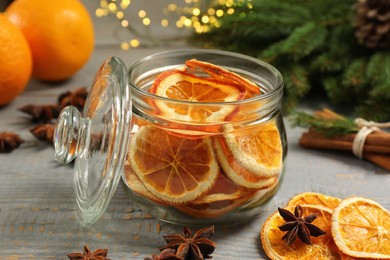 Photo of Glass jar with dry orange slices and anise stars on grey wooden table