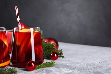 Photo of Delicious Sangria drink in glasses and Christmas decorations on grey textured table, closeup. Space for text