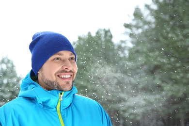 Portrait of happy man in snowy forest. Space for text