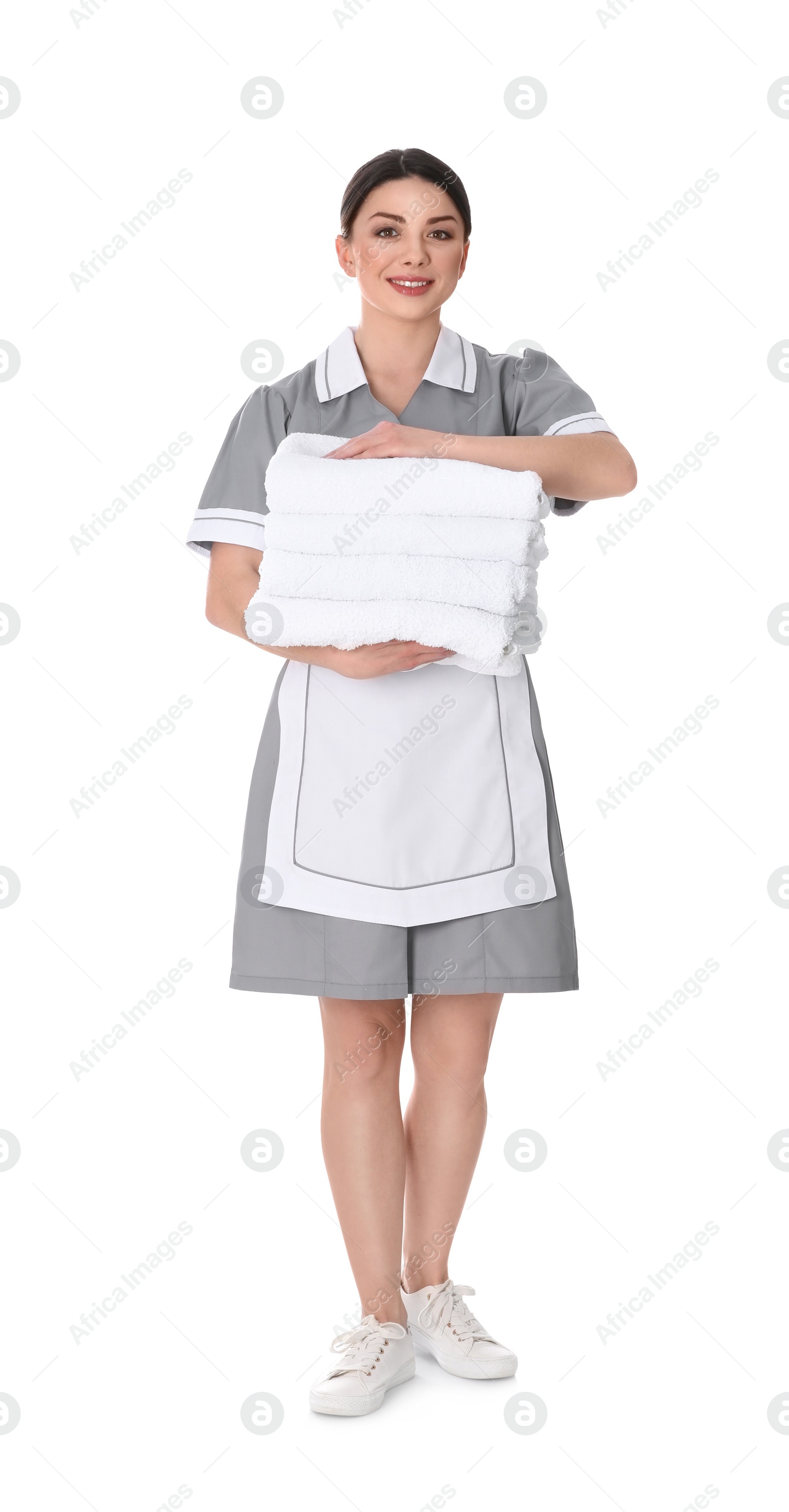 Photo of Young chambermaid holding stack of fresh towels on white background