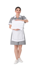 Young chambermaid holding stack of fresh towels on white background