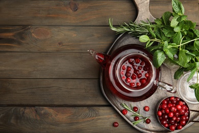 Photo of Tasty hot cranberry tea and fresh ingredients on wooden table, top view. Space for text