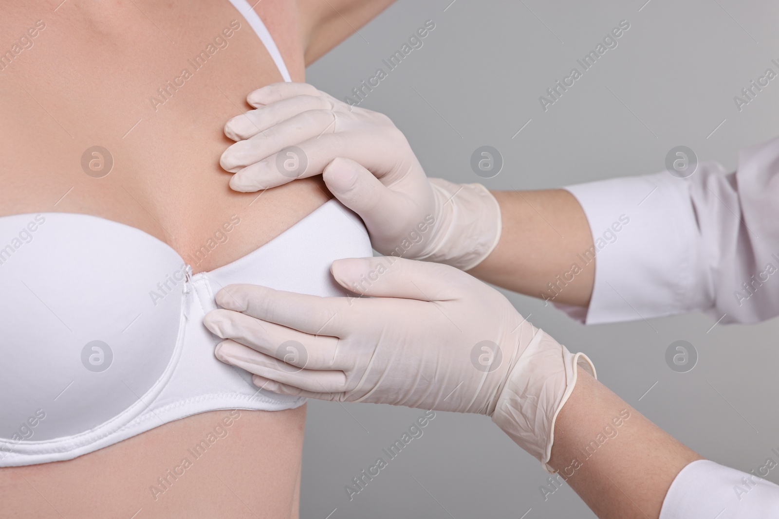 Photo of Mammologist checking woman's breast on gray background, closeup