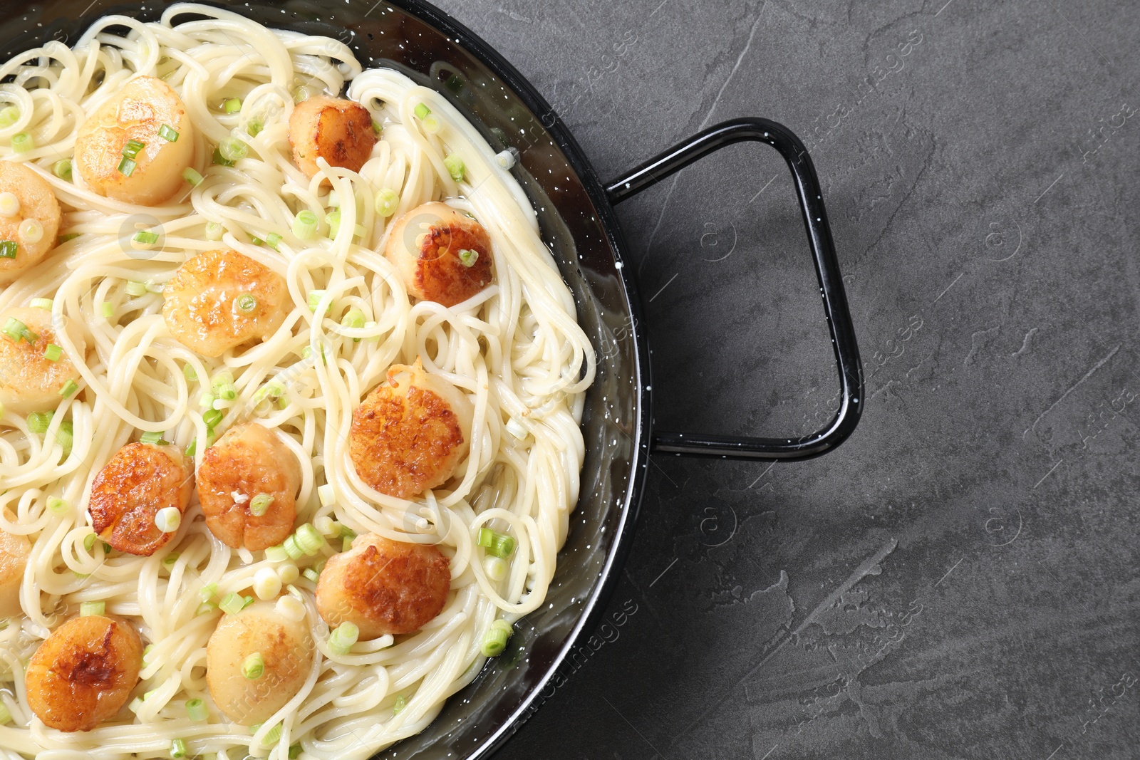 Photo of Delicious scallop pasta with green onion on grey table, top view