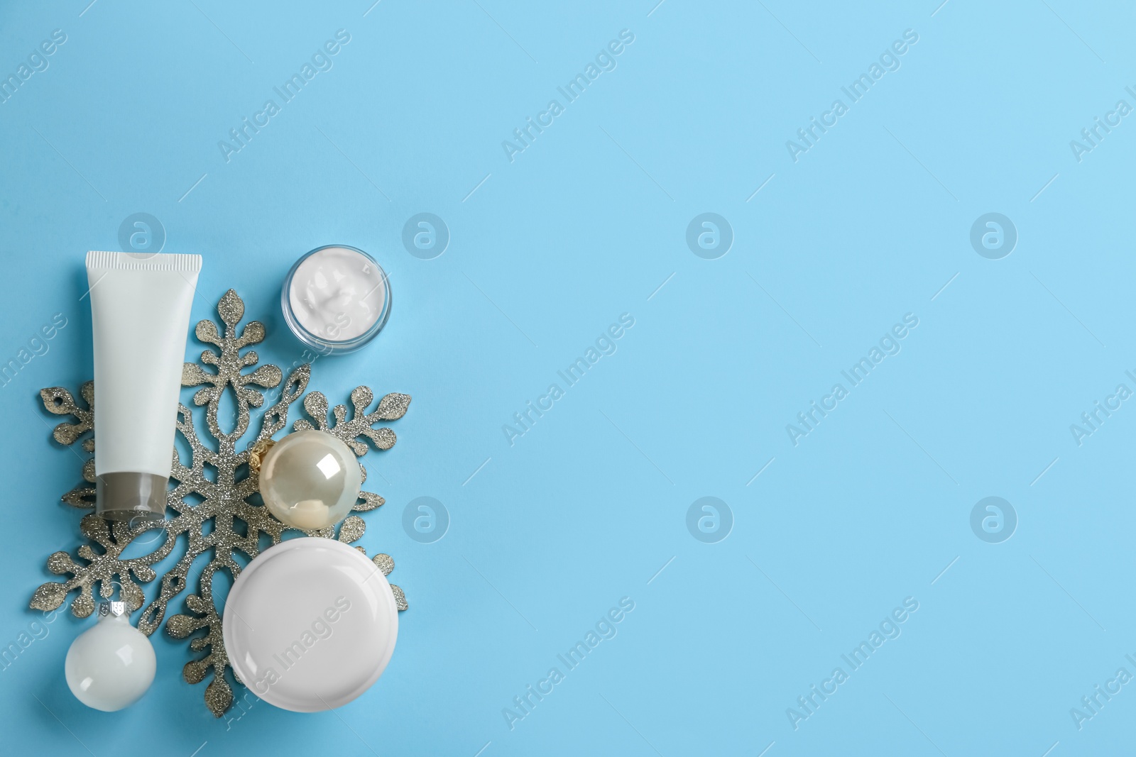Photo of Flat lay composition with different cosmetic products on light blue background, space for text. Winter care