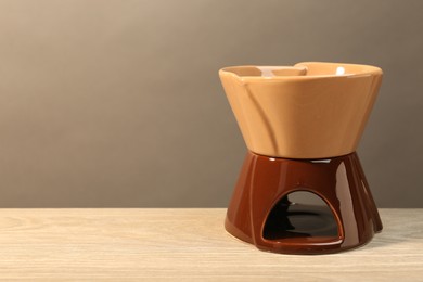 Fondue pot with burner on wooden table, space for text