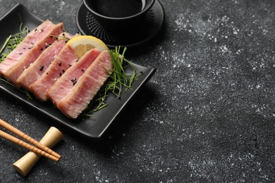Pieces of delicious tuna steak served on black table. Space for text