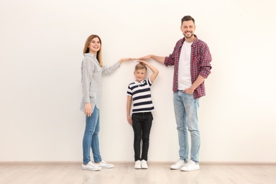 Photo of Parents measuring their son's height indoors