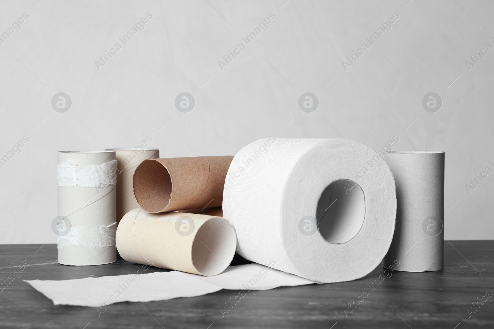 Photo of Full and empty toilet paper rolls on table against grey background