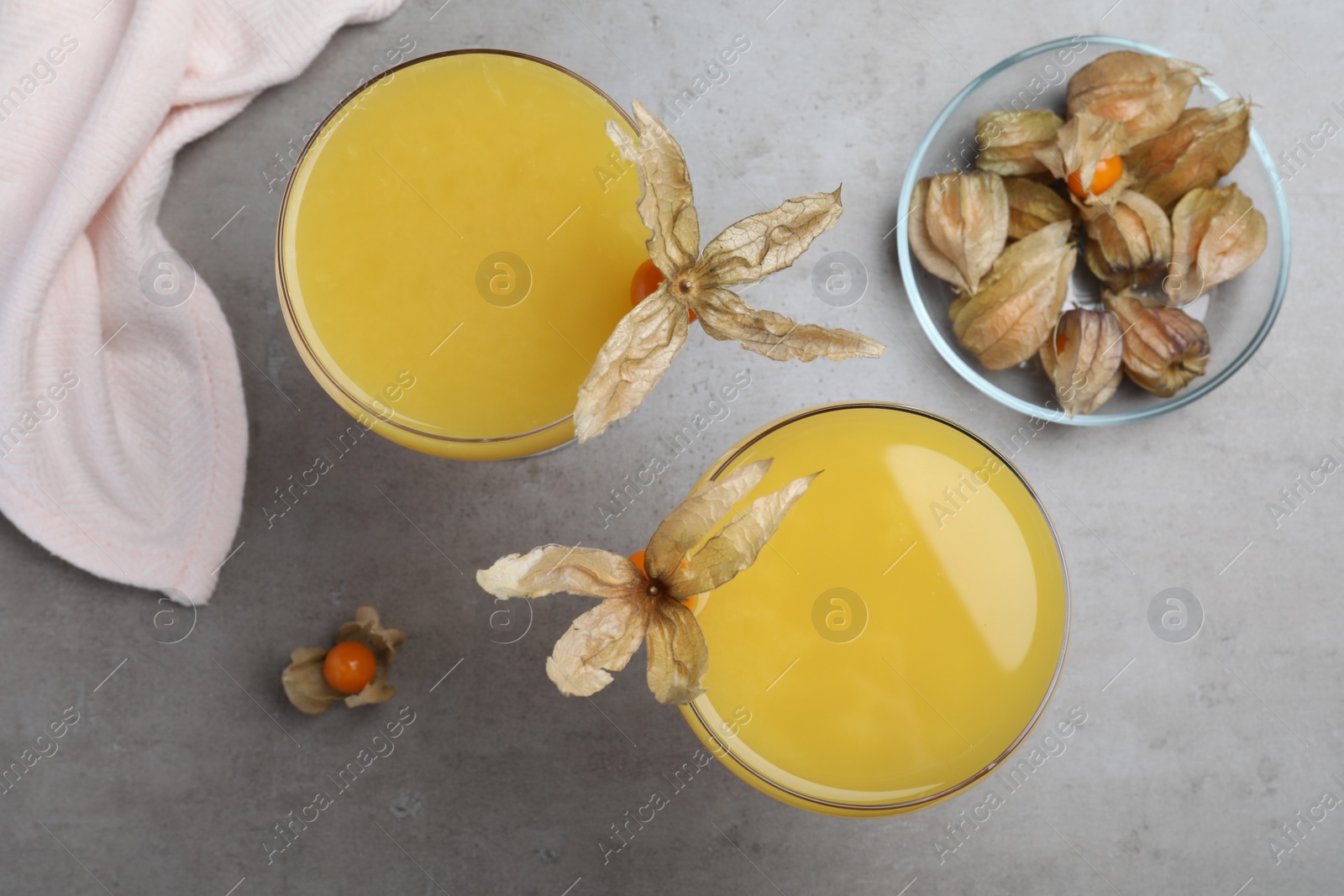 Photo of Tasty cocktail decorated with physalis fruits on grey table, flat lay