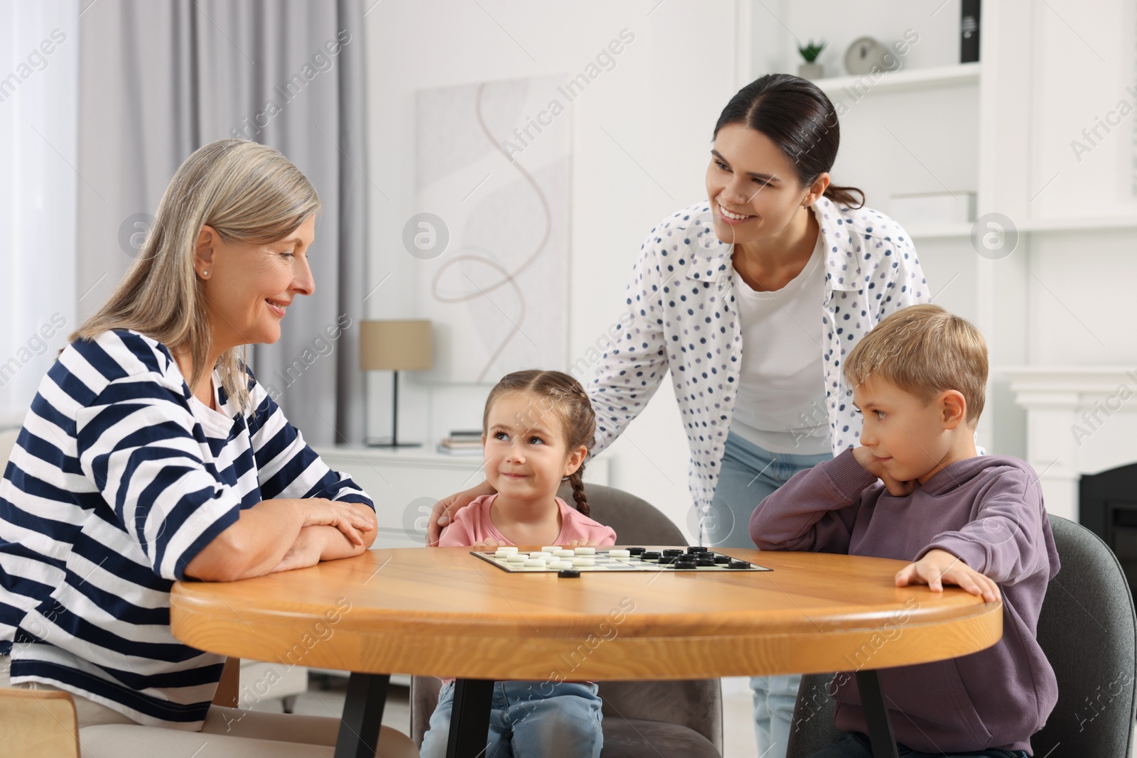 Photo of Family playing checkers at wooden table in room