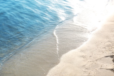 View of sea water and beach sand on sunny summer day