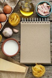 Photo of Blank recipe book and different ingredients on wooden table, flat lay. Space for text