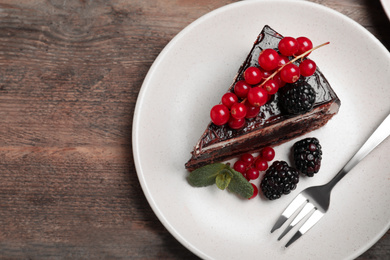 Photo of Tasty chocolate cake with berries on wooden table, top view