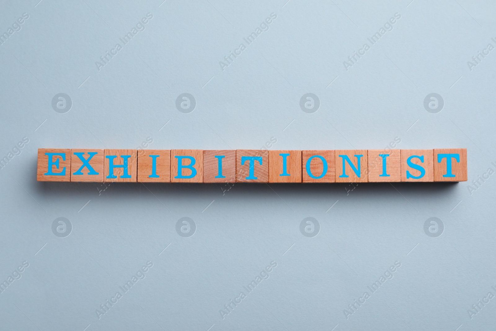 Photo of Word EXHIBITIONIST made with wooden cubes on white background, flat lay