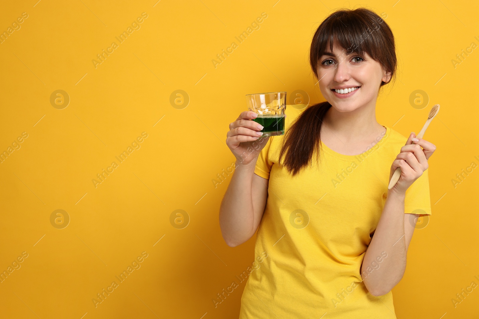 Photo of Young woman with mouthwash and toothbrush on yellow background, space for text