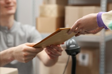 Photo of Worker giving parcel to woman at post office, closeup