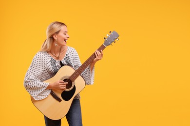 Photo of Happy hippie woman playing guitar on yellow background. Space for text
