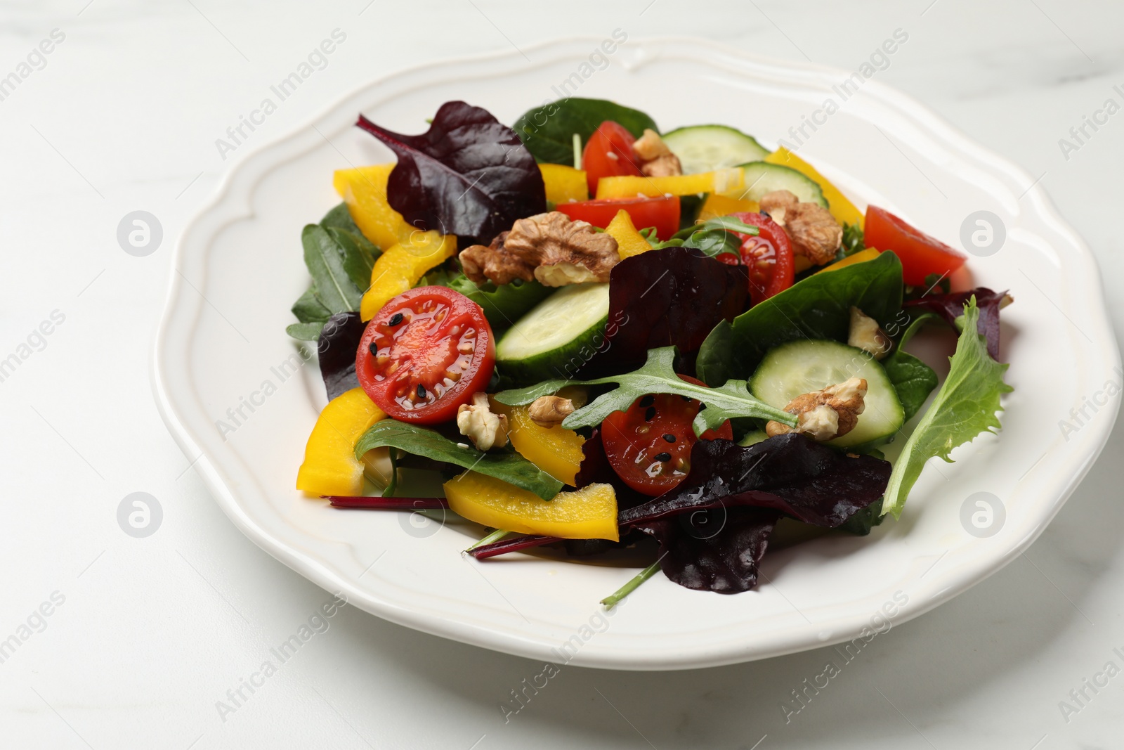 Photo of Tasty fresh vegetarian salad on white marble table, closeup