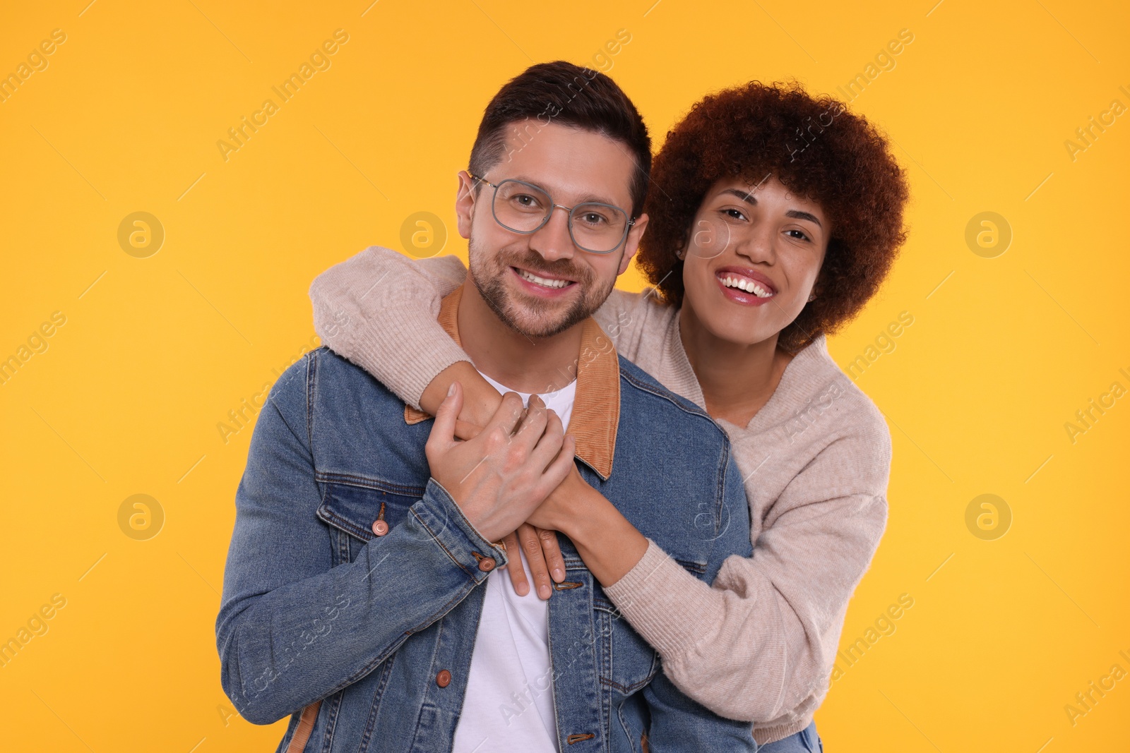 Photo of International dating. Happy couple hugging on orange background