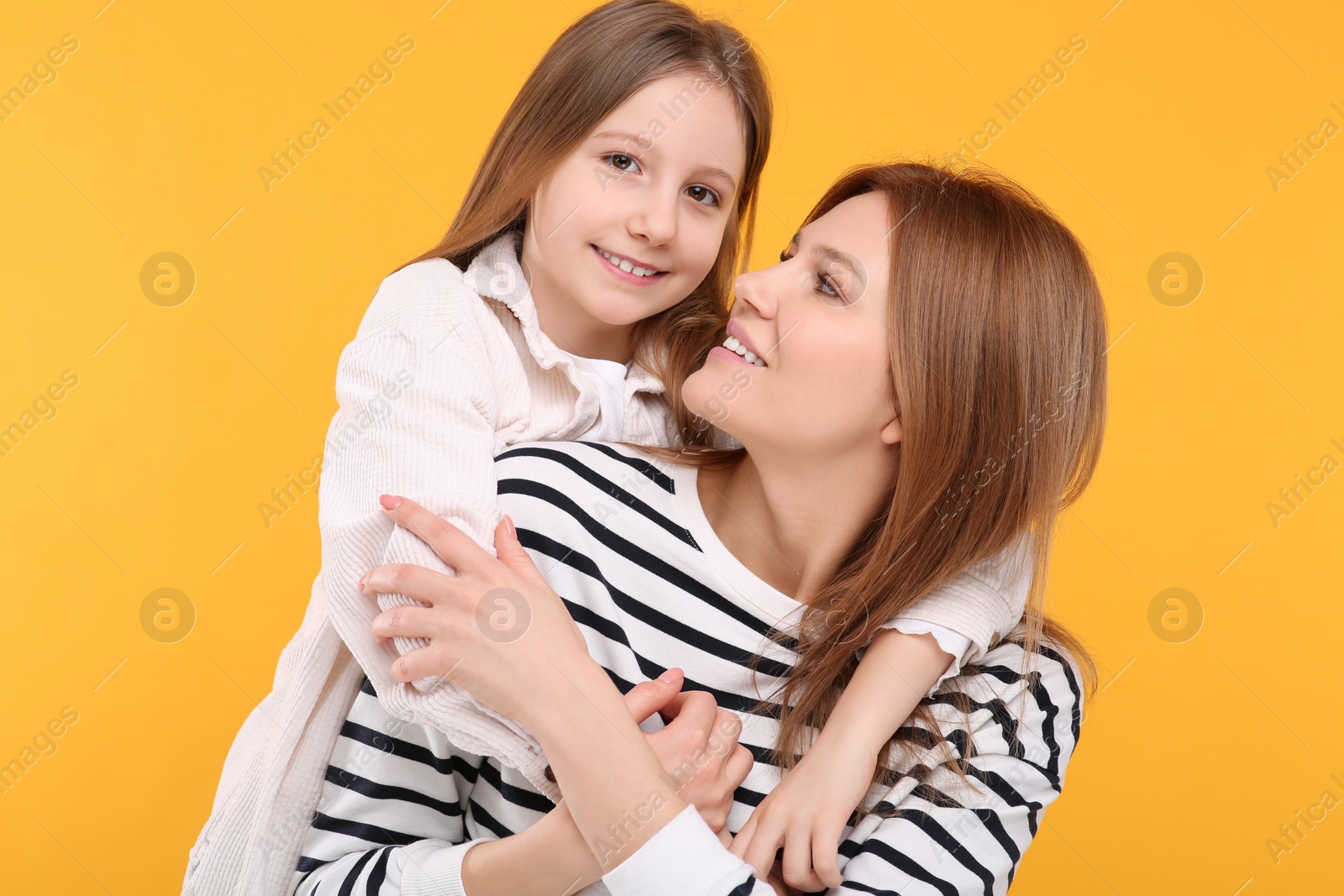 Photo of Portrait of happy mother and her cute daughter on orange background