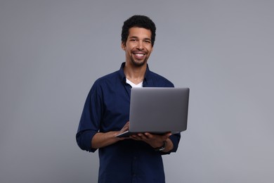 Happy man with laptop on grey background