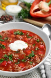 Bowl of delicious stuffed pepper soup on table, closeup