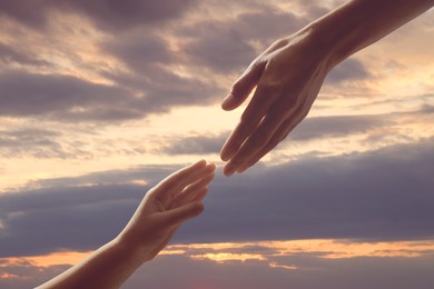 Image of Godparent with child and beautiful sky with clouds at sunset on background, closeup