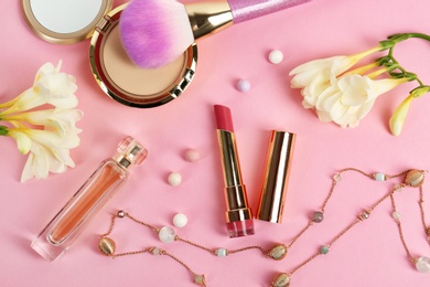 Flat lay composition with bright lipstick, flowers and accessories on pink background