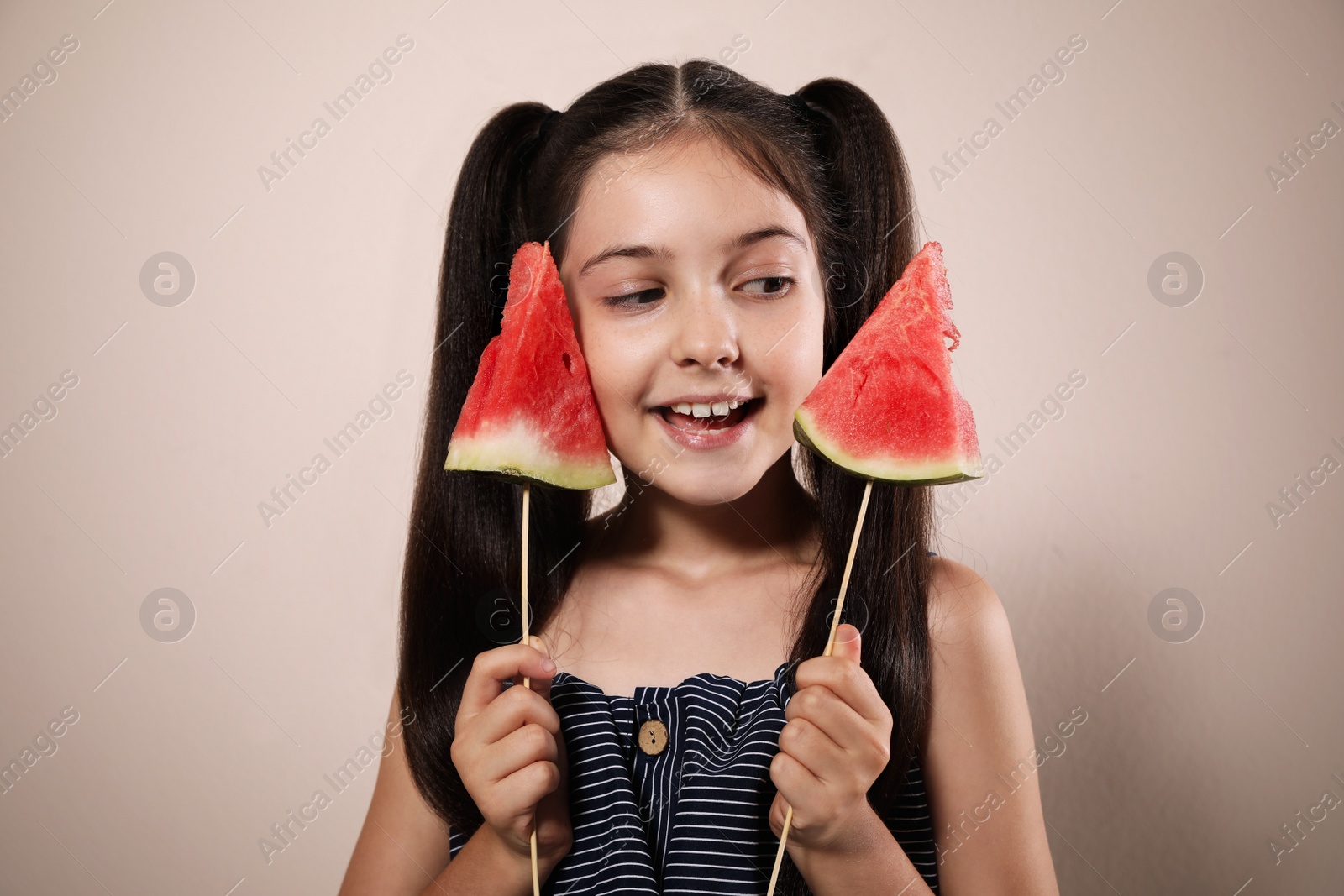 Photo of Cute little girl with watermelon on beige background