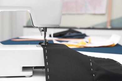 Sewing machine with fabric on table in tailor workshop, closeup