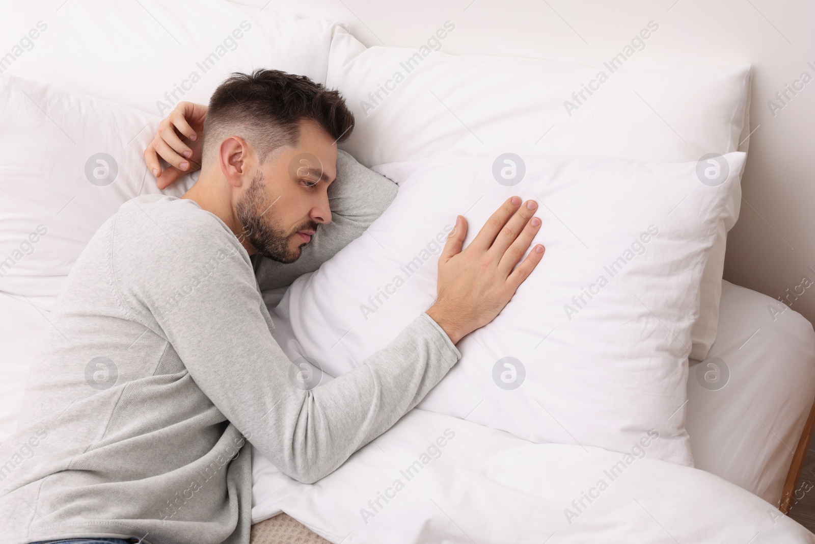 Photo of Upset man lying on bed. Loneliness concept