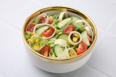 Photo of Bowl of tasty salad with leek, tomatoes and cucumbers on white tiled table, closeup